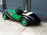 a green and black car parked in front of a garage