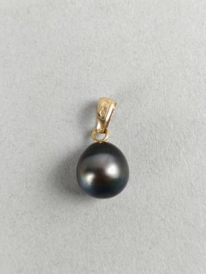 a close up of a black pearl pendant on a white surface