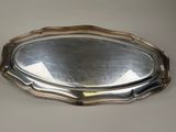 an oval silver tray with a handle on a table