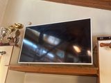 a flat screen tv sitting on top of a wooden shelf