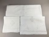 quatre serviettes de table en lin blanc ornées de monogrammes brodés