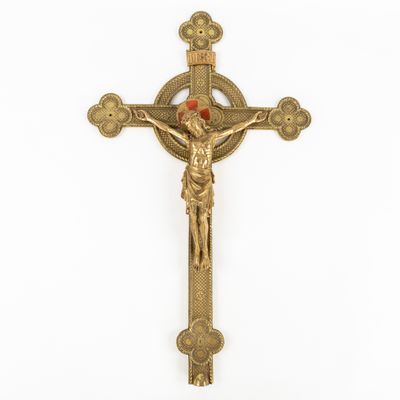 a gold crucifix with a red stone in the center