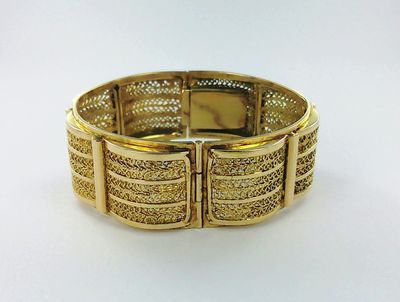 gros plan d'un bracelet en or sur une surface blanche