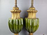 une paire de vases verts et dorés posés sur des socles en bois, sur fond gris