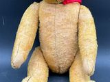un ours en peluche marron avec un nœud rouge autour du cou