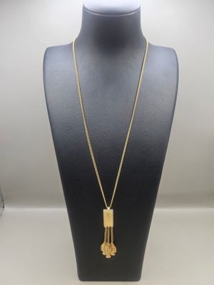a gold necklace with a long tassel hanging from it ' s neck