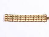 a close up of a gold bracelet on a white surface
