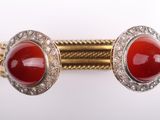 a close up of a pair of cuff bracelets with red stones