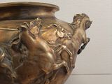 a bronze vase with horses on it on display