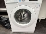 a white washing machine sitting on the floor next to a trash bag