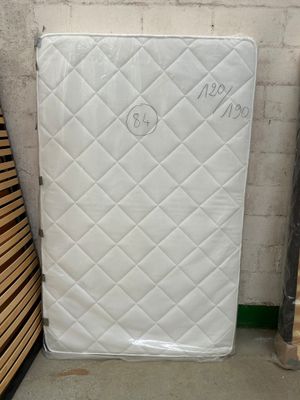 a mattress that is sitting next to a pile of wood