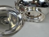 a silver plate with a silver lid on a table