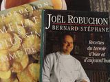 deux livres posés sur une table, à côté d'une tasse de thé et d'une assiette de nourriture