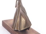 bronze statue of a woman in a long dress on a wooden base