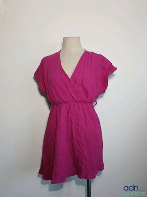 une robe rose posée sur un mannequin contre un mur blanc