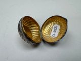 two silver and gold bowls on a white surface with a price tag