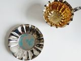 two silver and gold dishes on a white table
