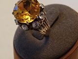 une image représentant une bague ornée d'une grosse citrine entourée de diamants