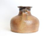 a brown vase that is sitting on a white surface