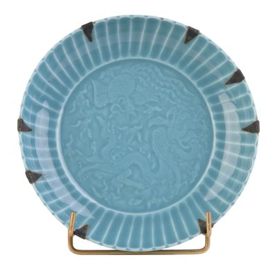 assiette bleue et blanche avec un pied doré sur fond blanc