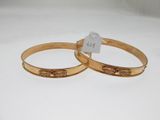 two gold tone bang bracelets with a tag on each of them