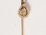 a close up of a gold and diamond broochle pin on a white surface