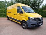 the yellow van is parked in the parking lot next to a hedge