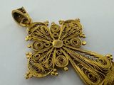 a close up of a gold pendant on a white surface