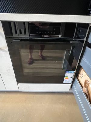 une personne debout devant un four dans une cuisine