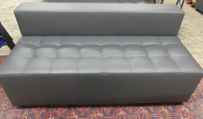grey leather sofa with foot rest on a rug in a store