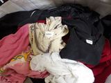 a pile of clothes that is sitting on a bed