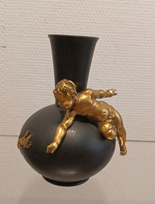 a black vase with a gold figurine on top of it
