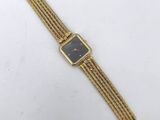 a gold plated watch with a black dial and a mesh bracelet
