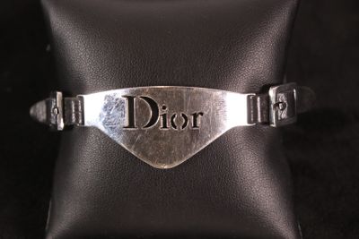 un gros plan d'un bracelet en argent sur lequel figure le mot « Dior »