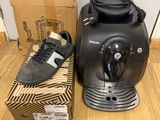 the coffee machine is next to a box of shoes on the floor