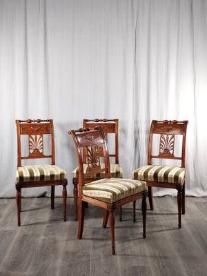 trois chaises en bois avec des assises rembourrées à rayures, devant un rideau blanc