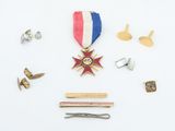 an image of a medal, pins, and a tie bar on a white surface
