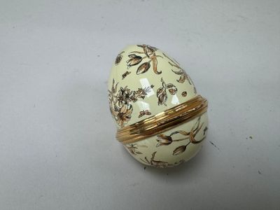 un œuf blanc et doré posé sur une surface blanche