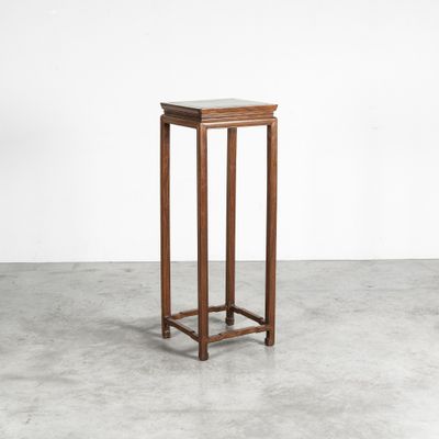 a small wooden table with a marble top on a concrete floor