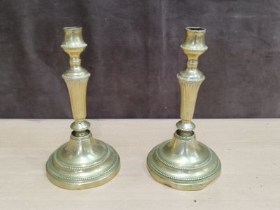 une paire de bougeoirs en laiton posés sur une table en bois, sur fond noir