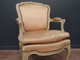 un vieux fauteuil avec une assise en cuir et un repose-pieds, placé face à un mur