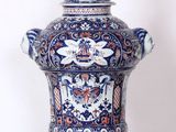 un vase bleu et blanc surmonté d'une bougie