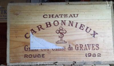 une caisse en bois sur laquelle est accrochée une pancarte indiquant « Château Carbonneux »