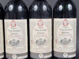 four bottles of red wine are lined up on a table