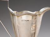 a silver pitcher with a handle on a table