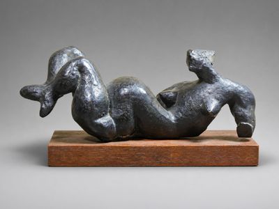 une sculpture représentant une femme allongée sur le dos sur un socle en bois