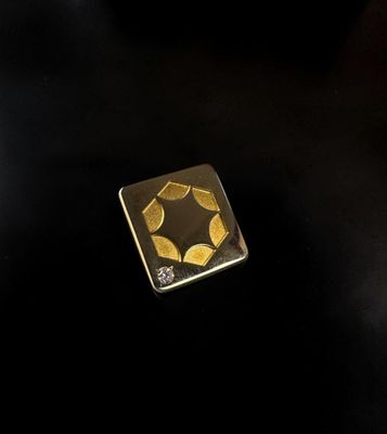a close up of a gold plated square shaped object on a black surface