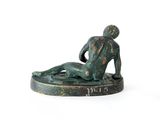 statue of a man laying on his back on a white surface
