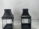pair of black metal lanterns with glass inserts on a white background
