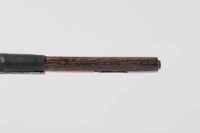 a wooden stick with a black handle on a white surface